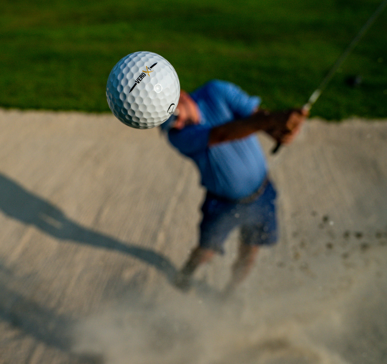 Golfspelare som chippar en golfboll ur en bunker